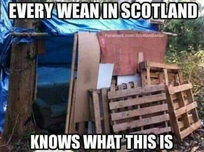Makeshift fort in Scotland with wooden pallets and tarpaulin, showcasing Scottish humor.