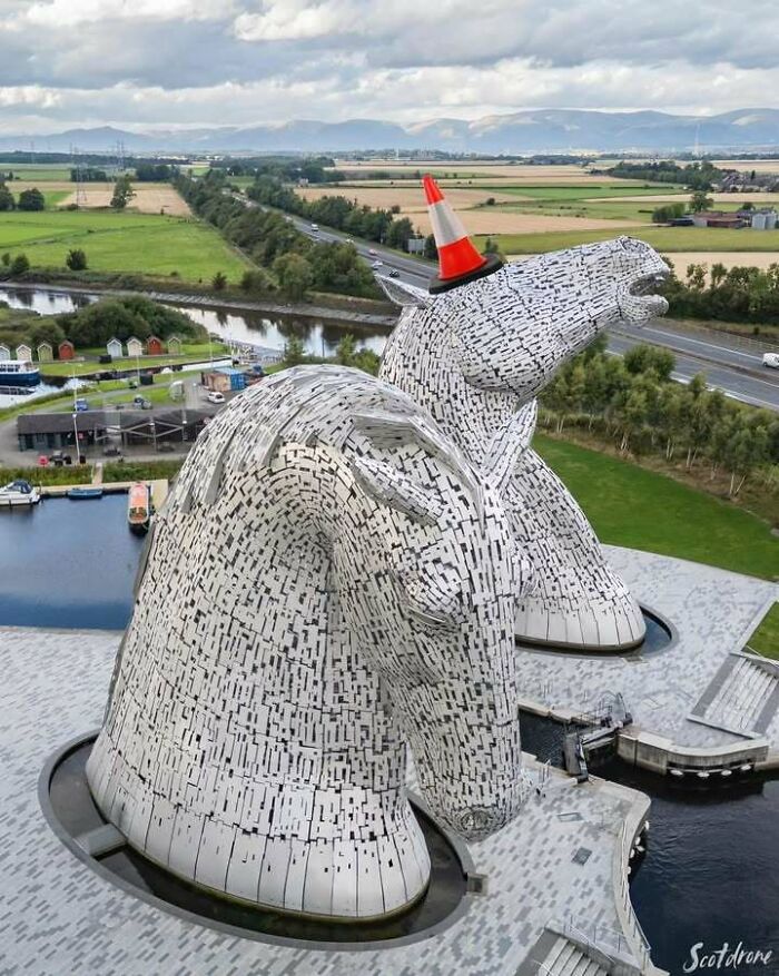 The Kelpies sculptures in Scotland with a humorous traffic cone on one head.