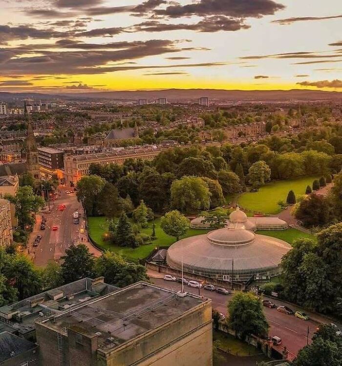 Sunset view of a lush park and historic architecture in Scotland, highlighting scenic beauty and cultural heritage.