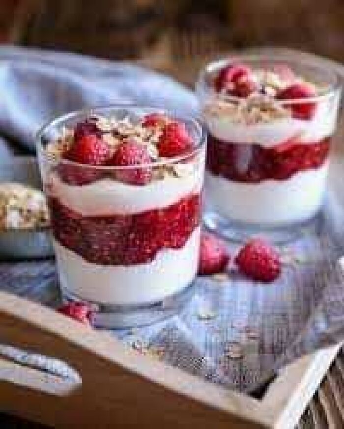 Traditional Scottish dessert in a glass with layers of whipped cream, raspberries, and toasted oats.