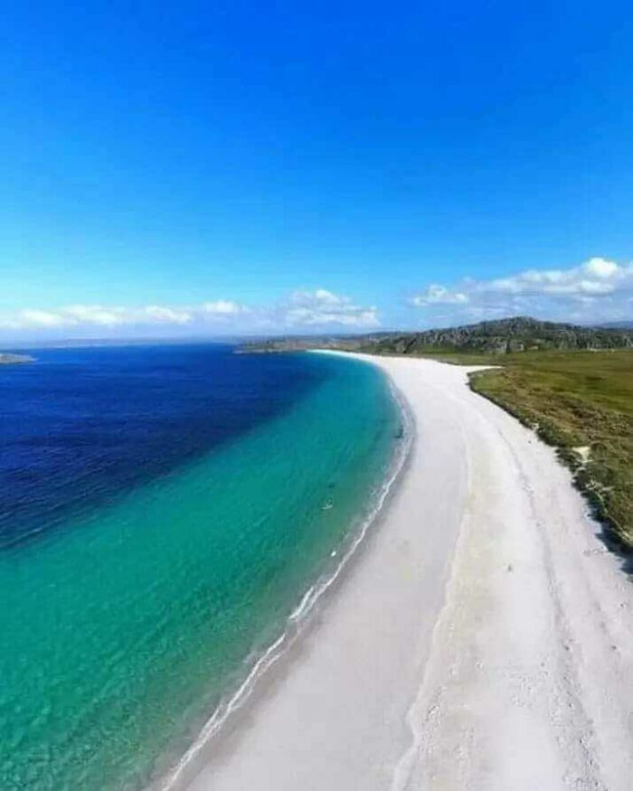 Pristine Scottish beach with turquoise water and white sand under a clear blue sky, highlighting Scotland’s natural beauty.