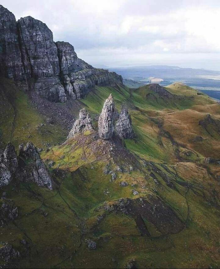 Majestic Scottish highlands with rocky formations and rolling green hills under a cloudy sky, showcasing Scotland's natural beauty.
