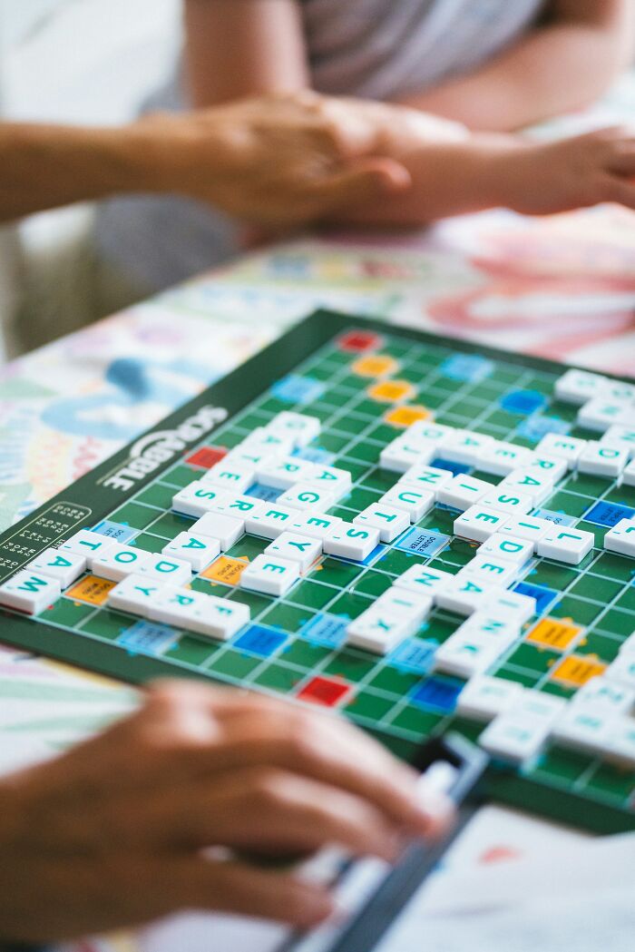 A game of Scrabble with words spelled out, capturing a moment of playful cringe.