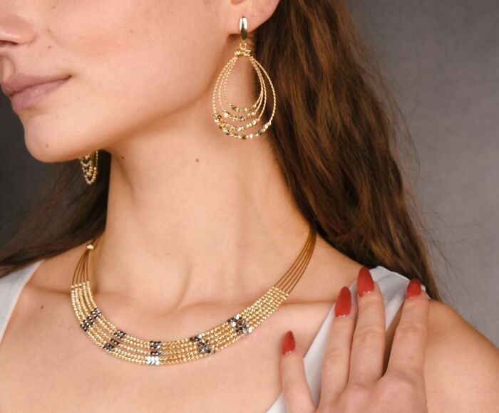 Gold jewelry trends for 2025: woman wearing elegant necklace and earrings, highlighting emerging fashion predictions.