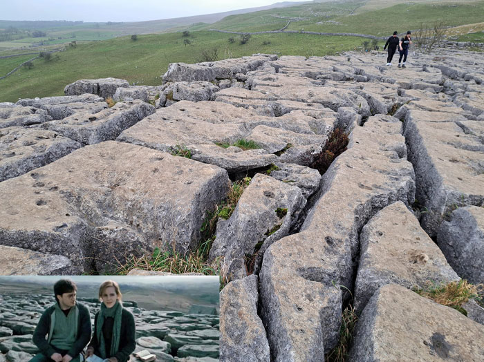 Limestone pavement famous from a popular movie scene, located in a picturesque landscape with two walkers in the distance.