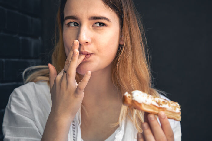 A woman contemplating while eating a pastry, highlighting moments of doubt in relationships.