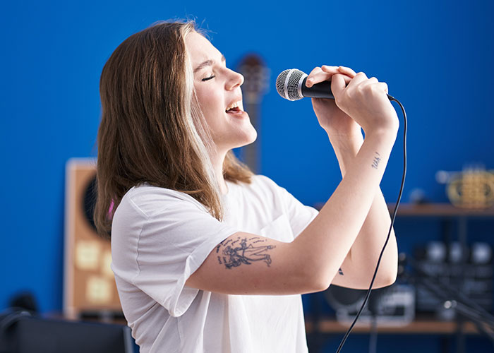 Person singing into a microphone in a studio, capturing the essence of reality TV shows' raw talent and emotion.