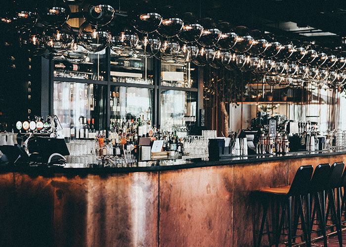 Stylish bar interior with ample seating and modern lighting, offering a reality TV show vibe.