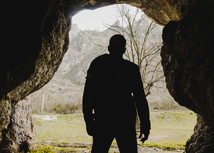 Silhouette of a person standing at a cave entrance, representing a mysterious look behind reality TV shows.