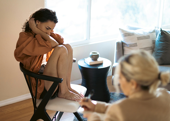 Woman upset after being uninvited from baby shower, sitting on chair indoors. Woman upset after being uninvited from baby shower, sitting on chair indoors.