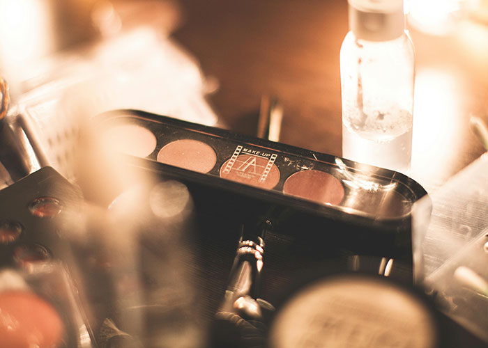 Makeup palette and skincare bottle on a table, highlighting shared beauty products.