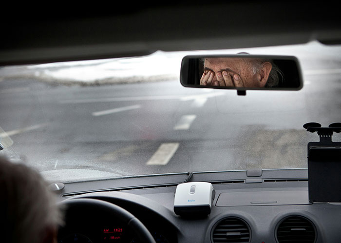 Driver looking stressed in rearview mirror at night, illustrating weird things seen while driving.