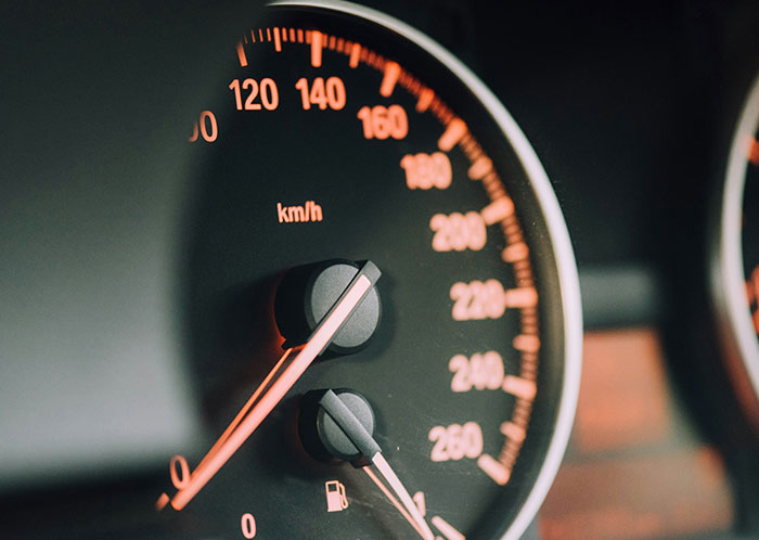 Close-up of a car speedometer glowing at night, highlighting driving experiences.