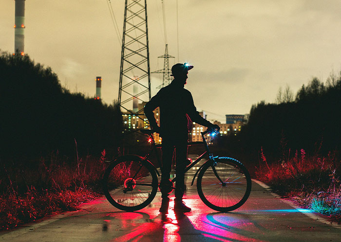Person on a bicycle at night, silhouetted against city lights, creating a mysterious driving scene.