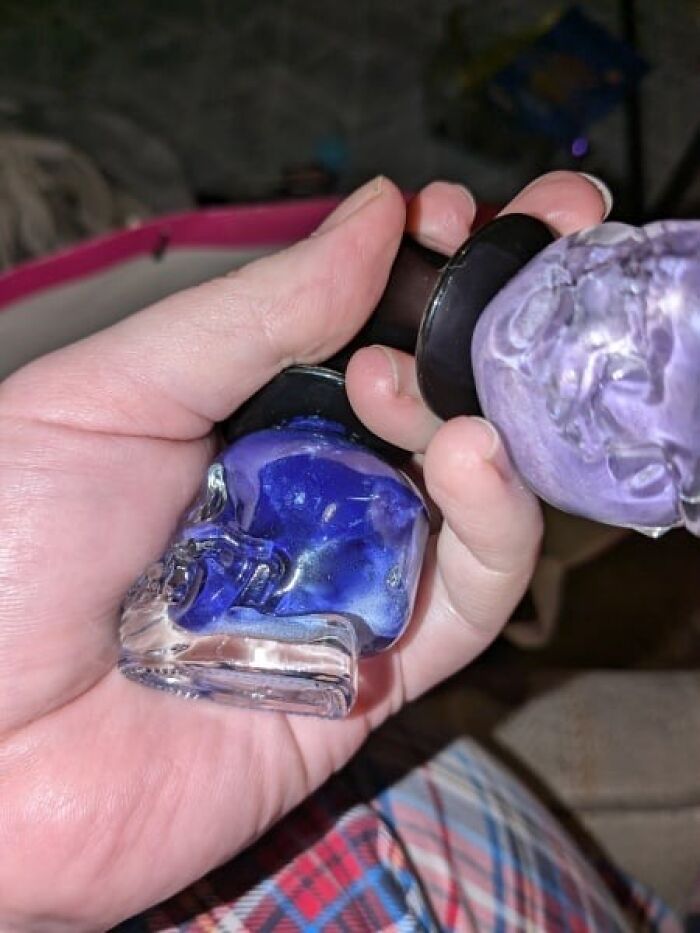 Hand holding expired Secret Santa gift, featuring blue and purple nail polish bottles.