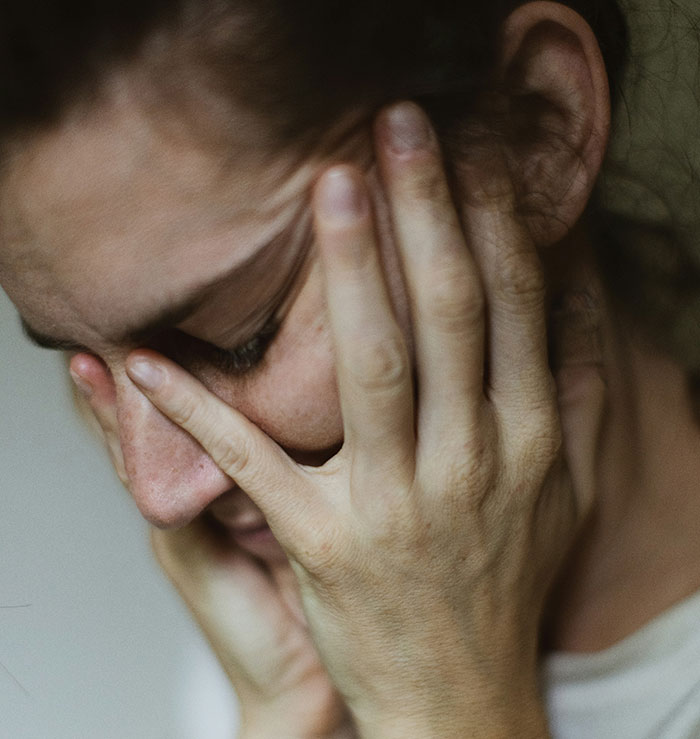 Person with head in hands, expressing family conflict emotions.