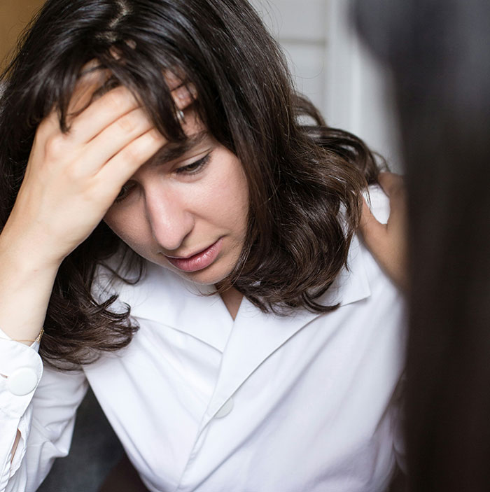 A woman in distress in a white shirt, depicting family toxicity and stress.