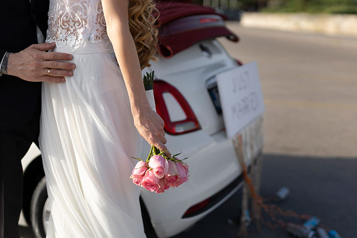 Bride holding flowers near a decorated car, symbolizing wedding tax chaos.