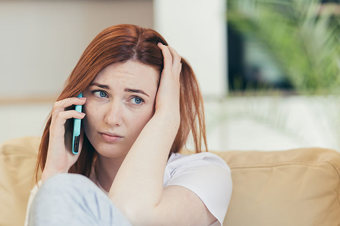 Woman on phone looking worried, related to the wedding tax mishap.