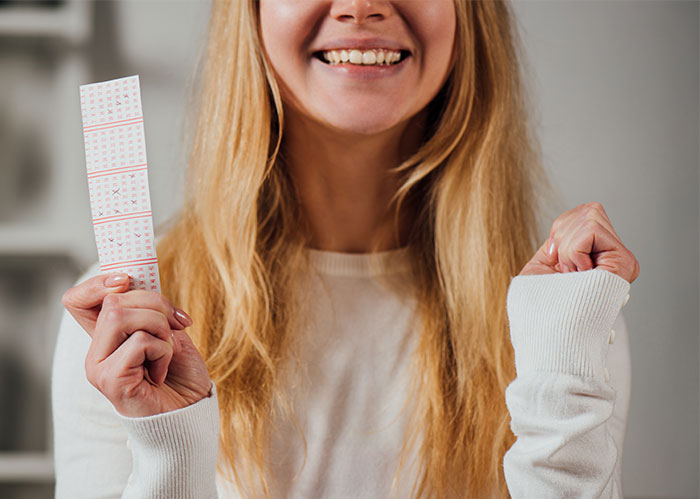 Woman celebrating while holding lottery ticket, expressing joy at lottery winnings. Woman celebrating while holding lottery ticket, expressing joy at lottery winnings.