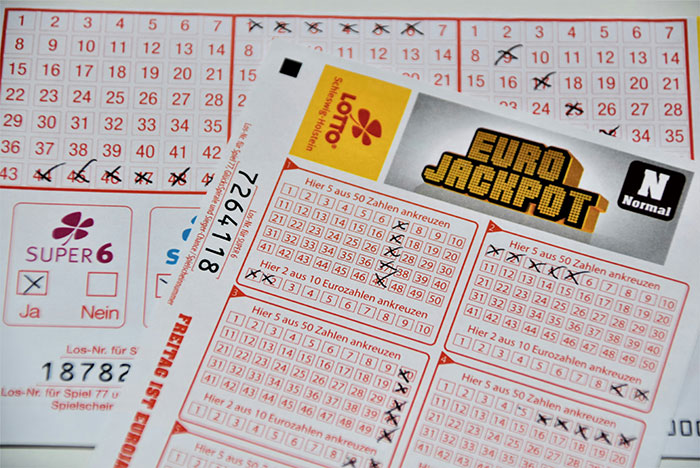 Various unchecked lottery tickets on a table, featuring Euro Jackpot and Super 6 games. Various unchecked lottery tickets on a table, featuring Euro Jackpot and Super 6 games.