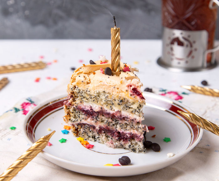 Slice of poppy seed cake with gold candle, on a festive plate. Slice of poppy seed cake with gold candle, on a festive plate.