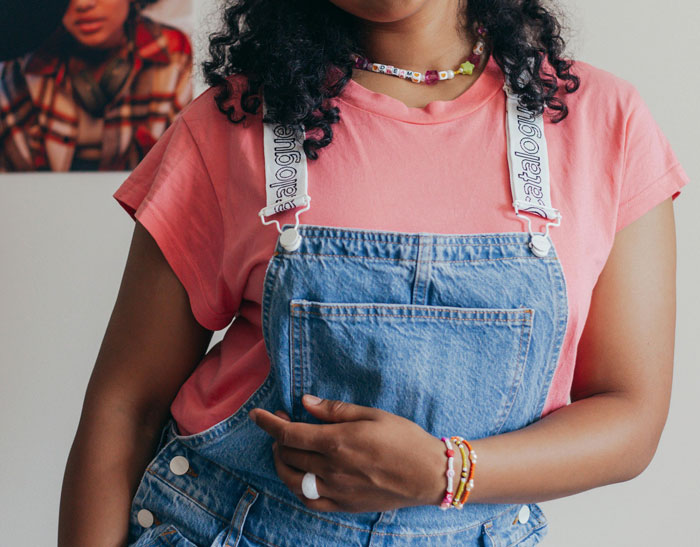 Young woman in denim overalls and pink shirt, showcasing casual style. Young woman in denim overalls and pink shirt, showcasing casual style.
