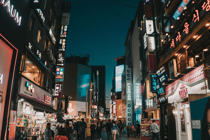 A bustling South Korean street at night, with illuminated signs and a crowd of people, reflecting urban life. A bustling South Korean street at night, with illuminated signs and a crowd of people, reflecting urban life.