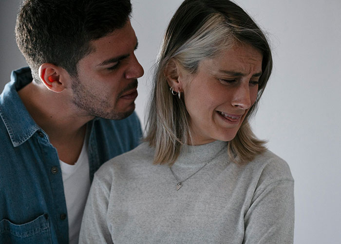 Man in blue shirt whispering to woman looking distressed, revealing something disturbing in marriage.