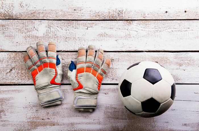 Soccer ball and goalie gloves on wooden floor, illustrating strangest delivery scenario.