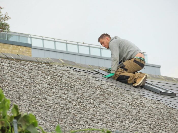 A delivery worker climbs a roof.