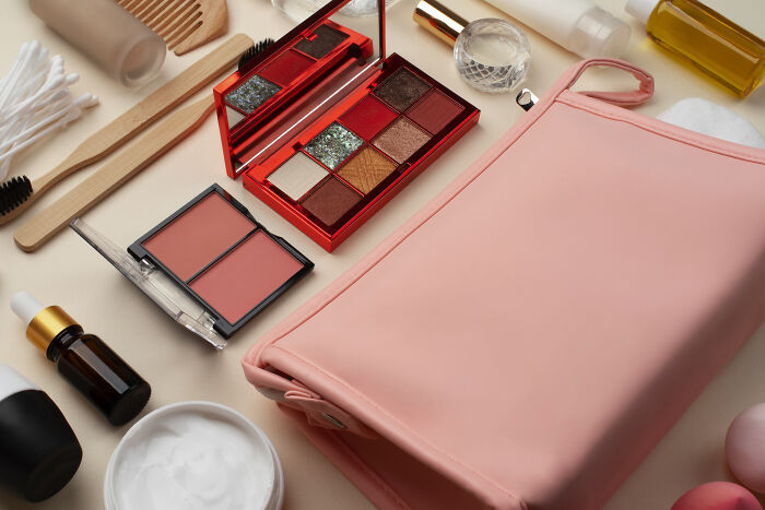 Cosmetics and toiletries arranged next to a pink bag.