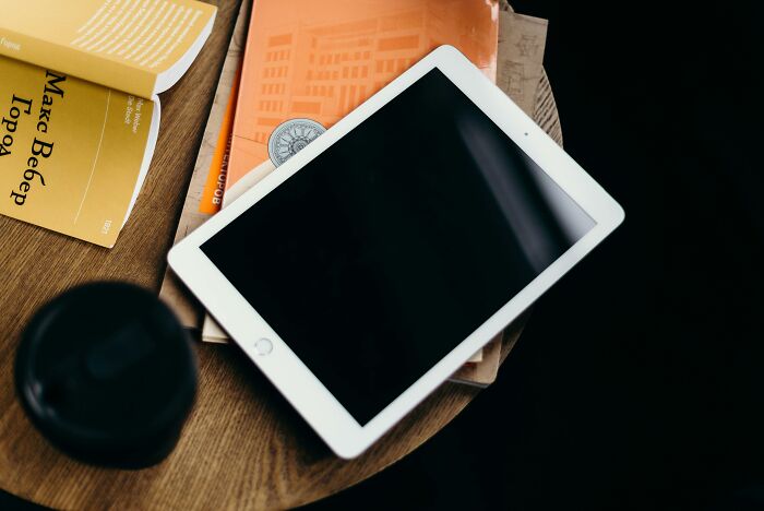 Tablet and books on a wooden table, representing strangest delivery stories.