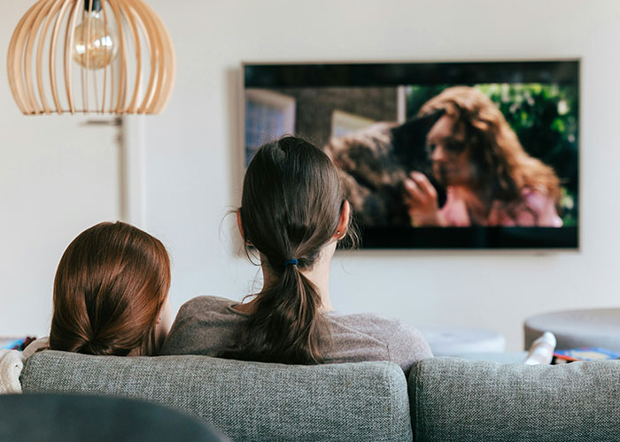 Two people sitting on a couch watching a movie, illustrating moments police were called on people for dumb reasons.