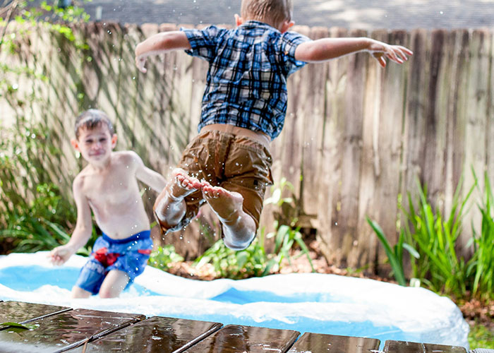 Kids having fun playing in a backyard pool on a sunny day.