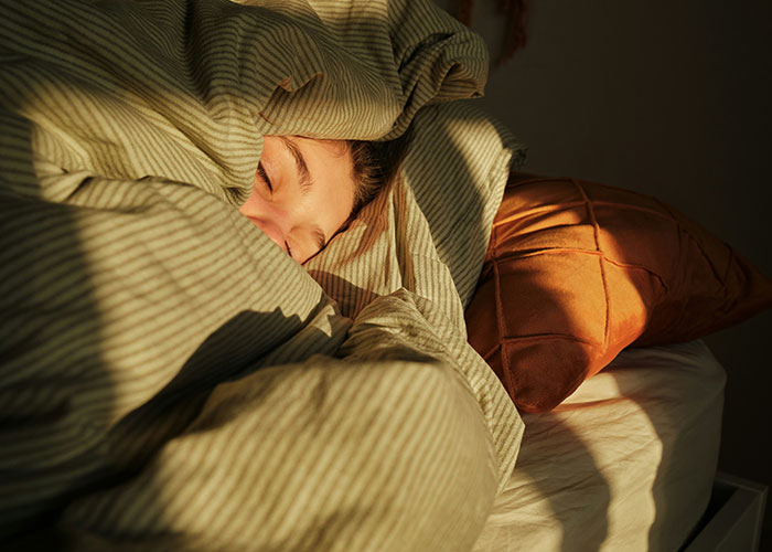 A person sleeping under a striped blanket, unaware of police involvement for a trivial reason.