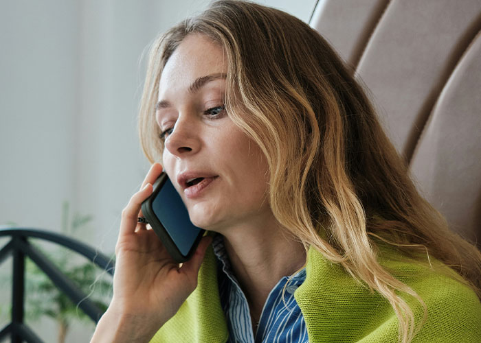 Young woman talking on phone looking concerned, illustrating police called on people for dumb reasons concept.