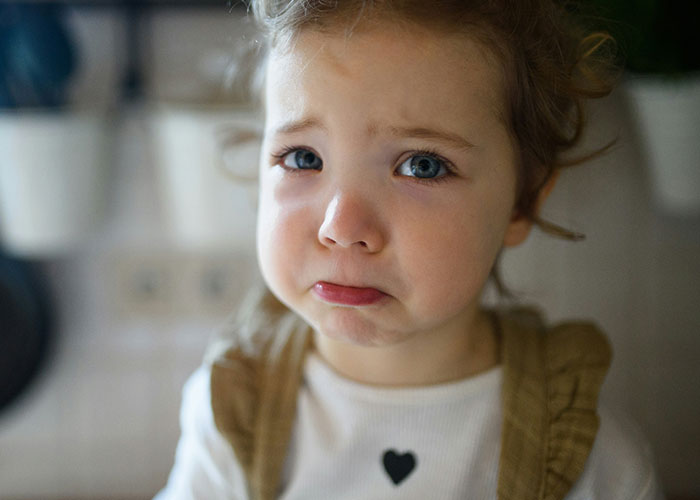 Close-up of a toddler with blue eyes making a sad face, illustrating times police were called for dumb reasons.