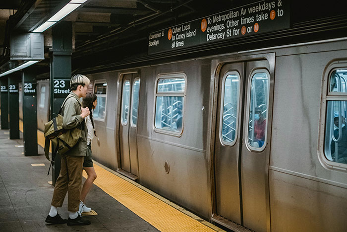 People standing on a subway platform by a train in a city setting.