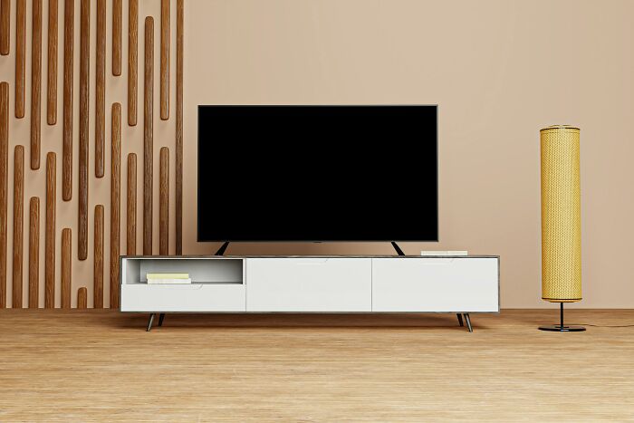 Modern living room with a sleek TV stand and a large flat-screen TV, highlighting a minimalist interior design.
