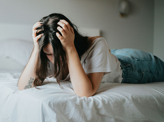 Woman lying on bed, stressed about family and money. Woman lying on bed, stressed about family and money.
