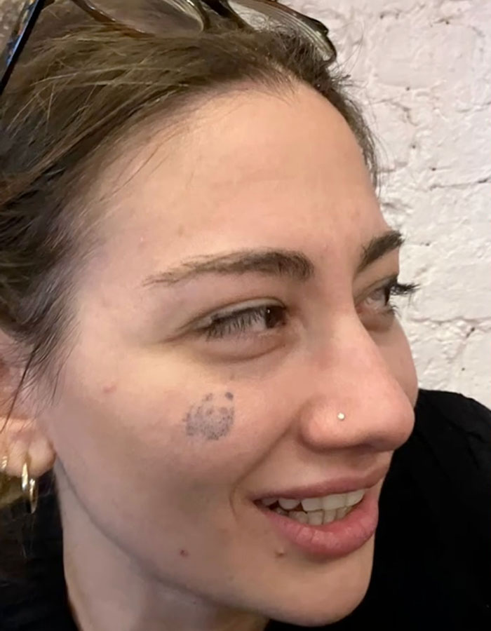 Woman with a temporary tattoo on her cheek, smiling and wearing glasses on her head. Woman with a temporary tattoo on her cheek, smiling and wearing glasses on her head.
