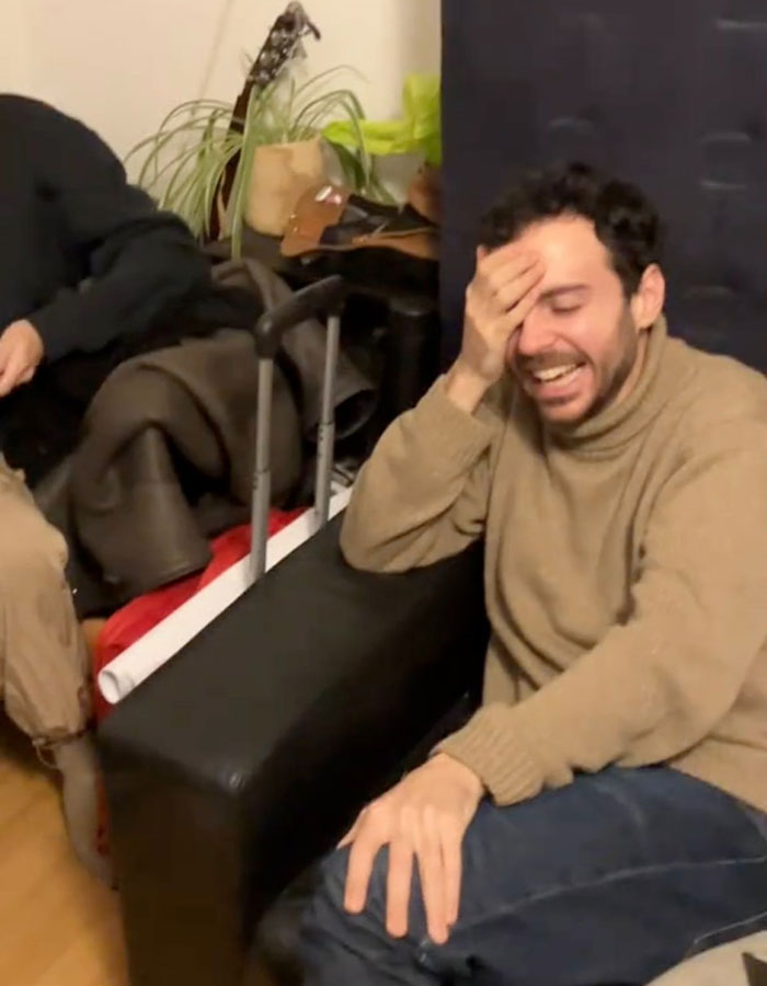 Man laughing on a couch with hand on face, suggesting temporary tattoos mishap. Man laughing on a couch with hand on face, suggesting temporary tattoos mishap.