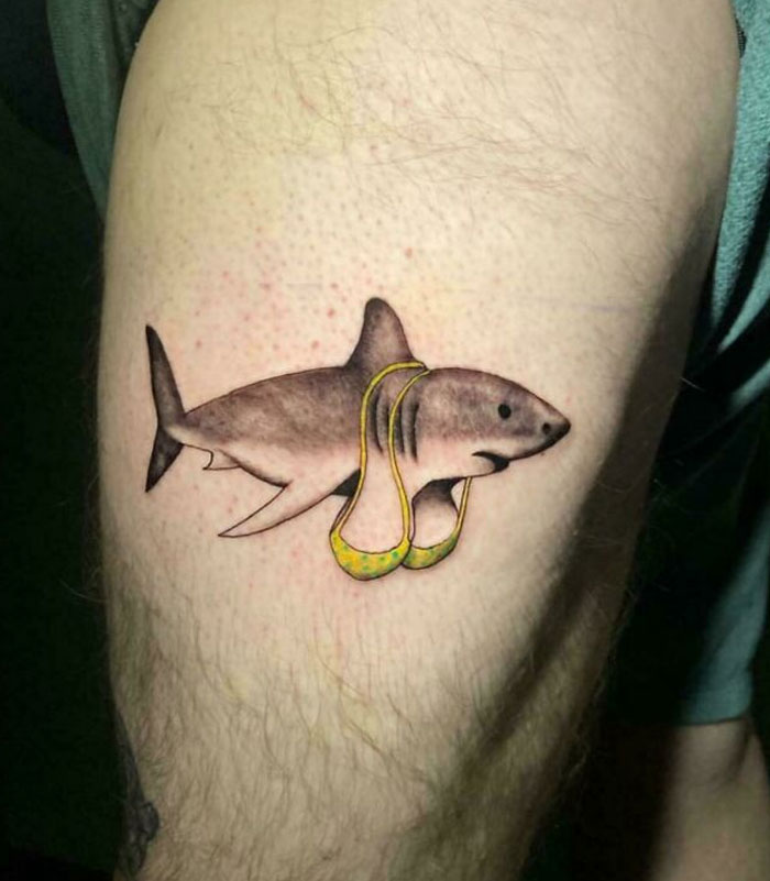 Shark tattoo with a bikini on a person's arm, featured among bad tattoos online.