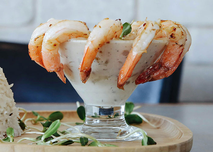 Shrimp cocktail in a glass with sauce, served on a wooden platter, ready for Thanksgiving dinner.