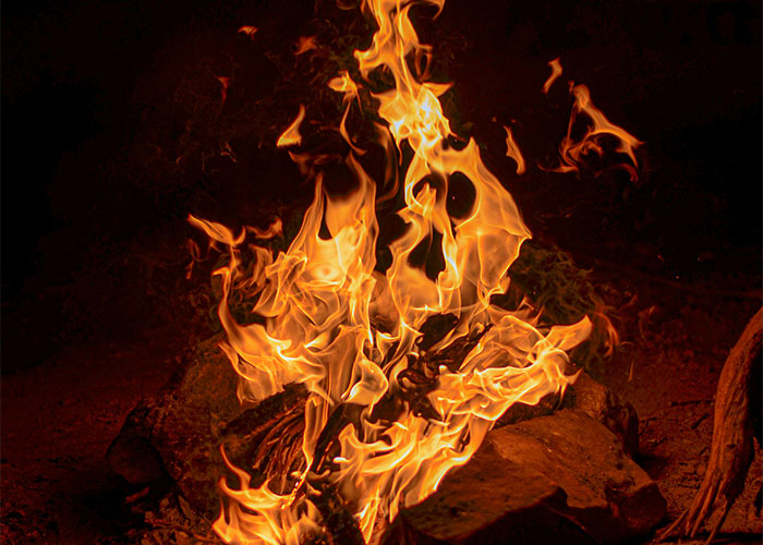 Thanksgiving campfire burning brightly in the dark, flames creating a warm and cozy atmosphere.
