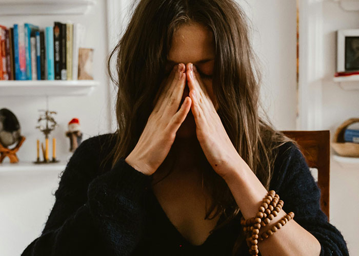 Woman feeling stressed at Thanksgiving, hands covering face, suggesting a terrible or hilarious turn.