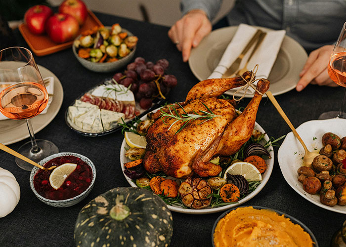 Thanksgiving dinner table with roasted turkey, cranberries, and wine, evoking a festive atmosphere.