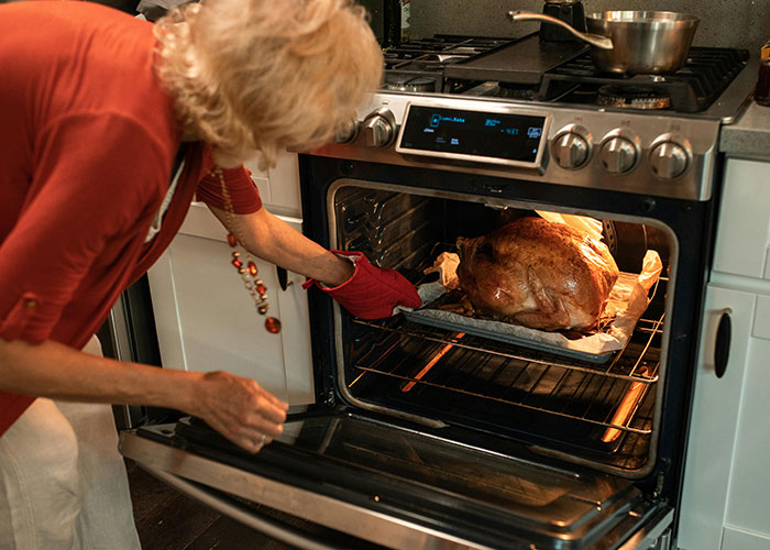 Person checking a turkey in the oven, capturing a moment of Thanksgiving cooking.