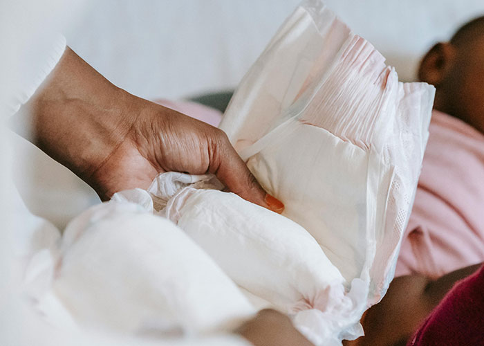 Thanksgiving diaper mishap as a hand holds a diaper near a resting child.